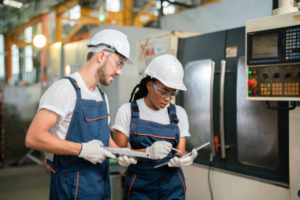 Mechanical technicians operative of cnc milling cutting machine center at tool workshop.